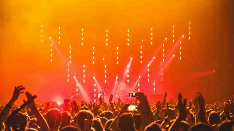Energetic crowd at a live concert with bright stage lights and hands raised in celebration., tags: die kreativität von frauen mit und - pexel